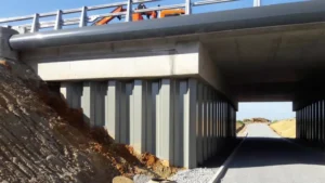 Steel sheet pile retaining wall supporting a bridge abutment and highway approach