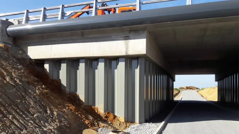 Steel sheet pile retaining wall supporting a bridge abutment and highway approach